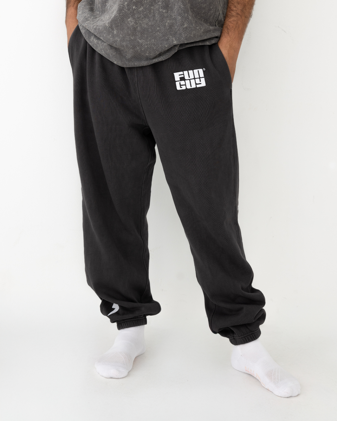 Person wearing black sweatpants with a logo on a white background