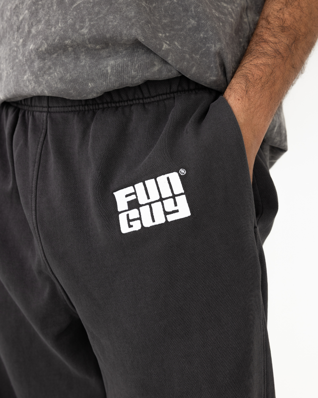 Black joggers with 'Fun Guy' logo worn by a person on a white background